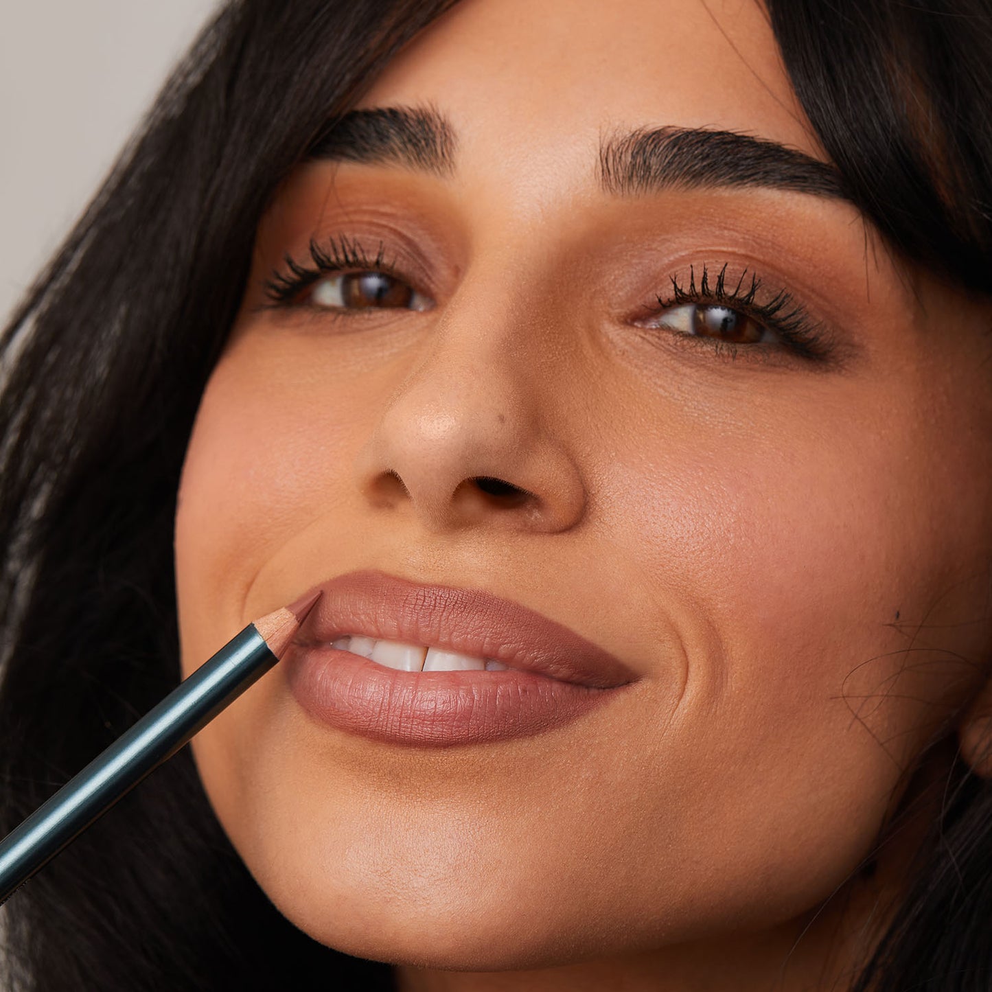 Person applying lipstick with a lip liner pencil.