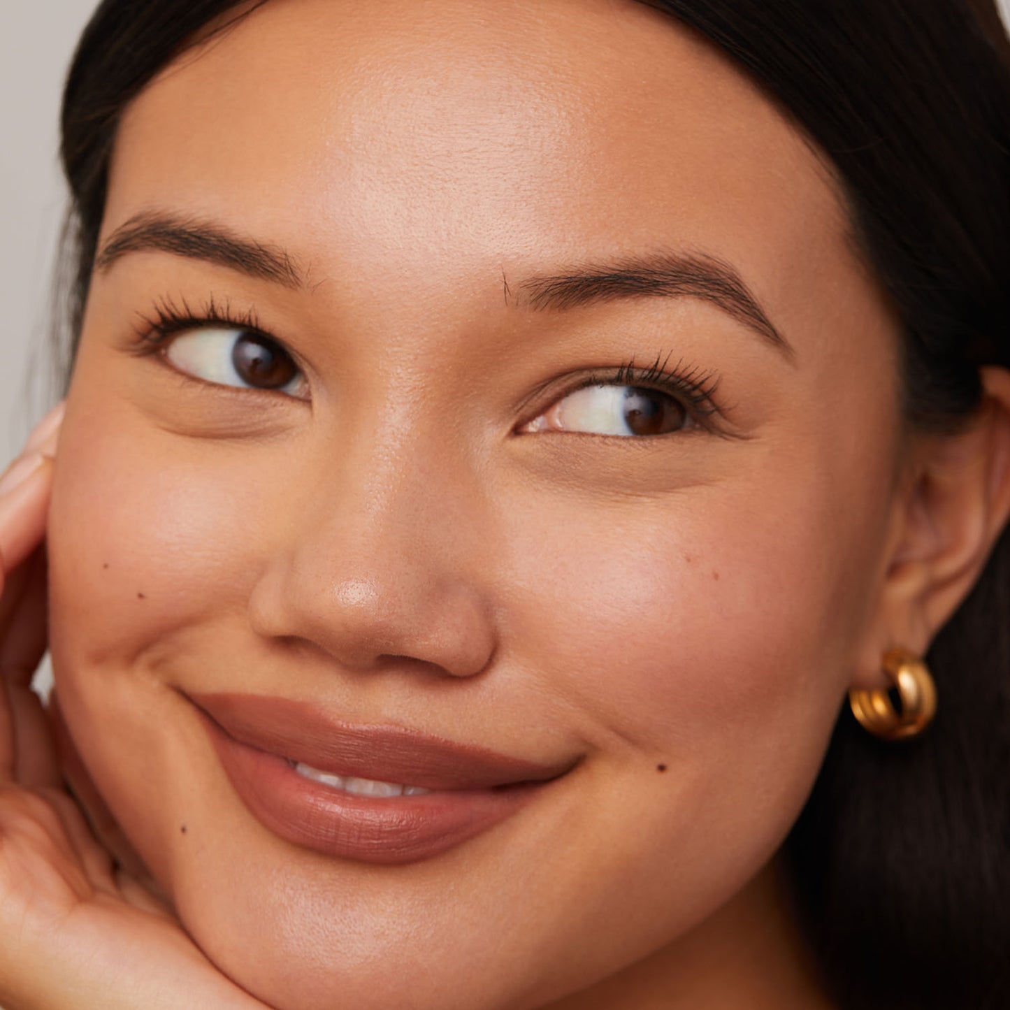 Close-up of a smiling person with gold hoop earring.