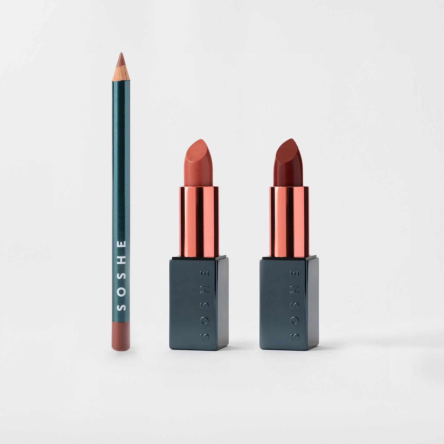 Lip pencil and two lipsticks in rose and red shades on a white background.