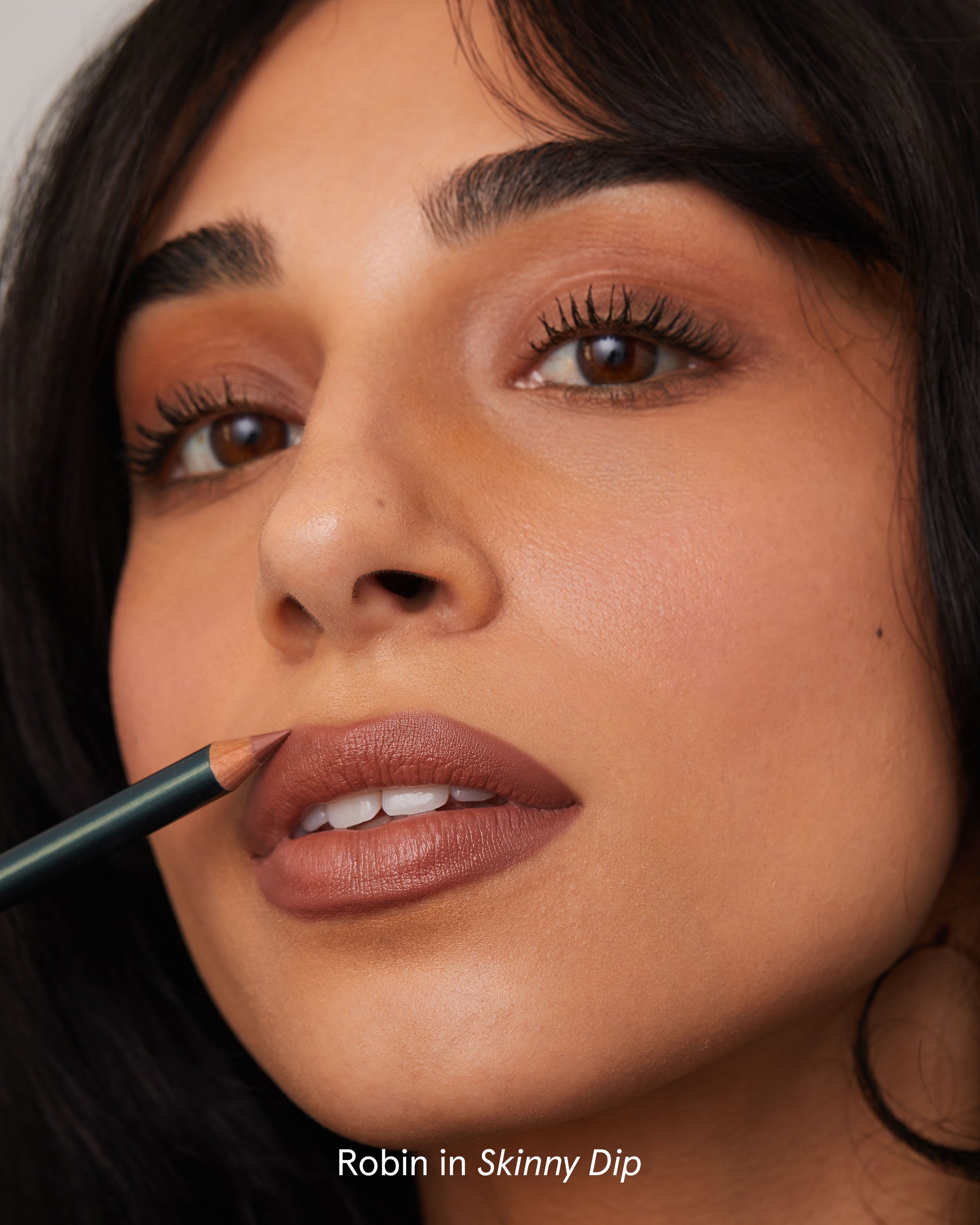 A person applying brown lip liner close-up.